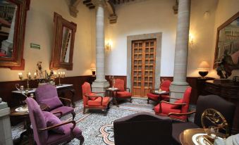 a luxurious living room with purple and red chairs , a wooden door , and pillars , as well as a marble floor at Hotel Luna