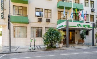 a green and white building with a street in front of it , featuring two bicycles parked on the sidewalk at Infinity Copacabana, Ex-APA Hotel