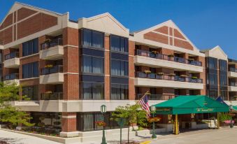 a large , modern apartment building with multiple balconies and an american flag in front , under a clear blue sky at The Townsend Hotel