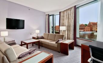 a modern hotel room with a large window , comfortable seating , and a tv on the wall at Hilton Gdansk