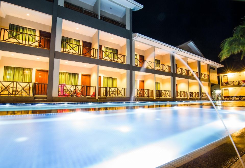 a nighttime view of a hotel with multiple floors , a large pool , and lit up windows at Summer Bay Resort, Lang Tengah Island