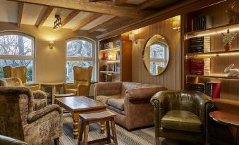 a cozy living room with a leather couch , chairs , and a coffee table in front of a window at Lion Quays Resort