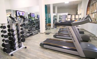 a well - equipped gym with various exercise equipment , including treadmills and weight machines , as well as a tv screen on the wall at Hotel Union