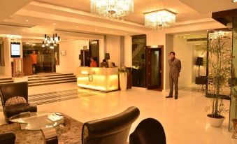 a man standing in a hotel lobby with a reception desk and a chandelier hanging from the ceiling at Hotel Downtown