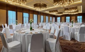 a large banquet hall with multiple round tables covered in white tablecloths and set for a formal event at Radisson Blu Hotel, Bamako