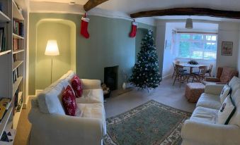 a living room with a white couch , christmas tree , and red stockings hanging from the ceiling at The White House Guest House