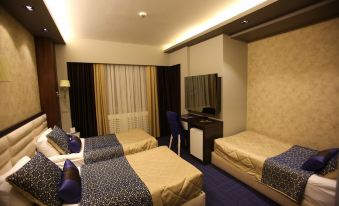 a hotel room with three beds , two of which are twin beds and one is a double bed at Prestige Hotel