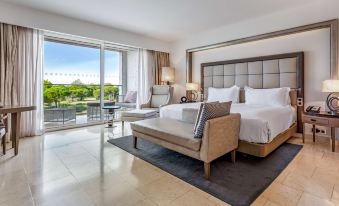 a luxurious hotel room with a king - sized bed , a couch , and a balcony overlooking a beautiful landscape at Conrad Algarve