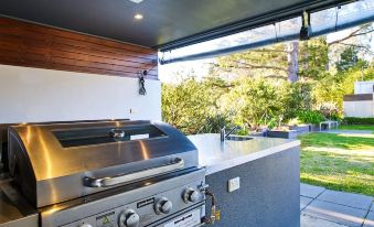 a modern outdoor kitchen with a grill and dining area , situated in front of a house at Myrtleford Motel on Alpine