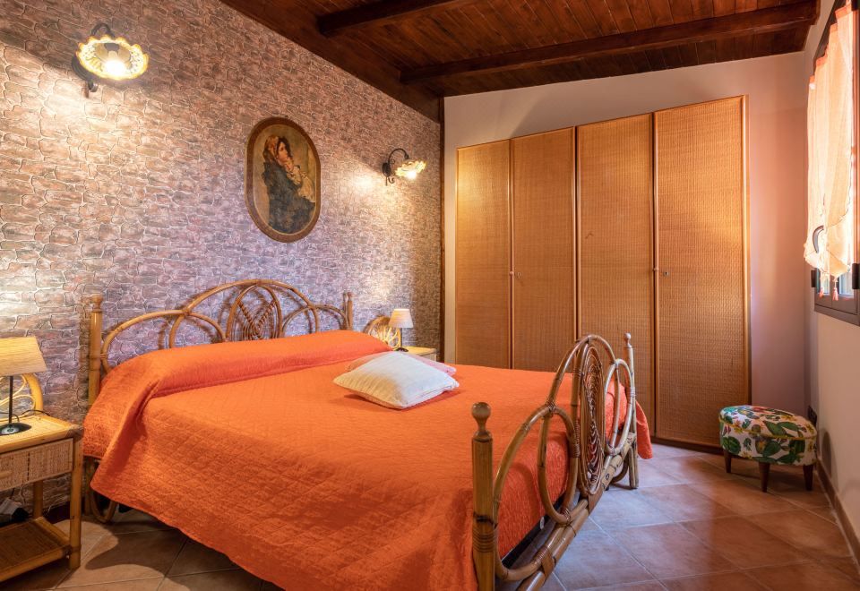 a bedroom with a wooden bed , an orange comforter , and a painting on the wall at Albert