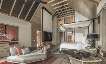 a modern bedroom with a large bed , a couch , and a tv . the room is well - appointed and appears to be a relaxing at Four Seasons Resort Maldives at Landaa Giraavaru