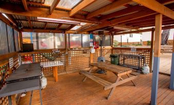 a wooden deck with a picnic table , grill , and other furniture , surrounded by windows that let in natural light at Discovery Parks - Hobart