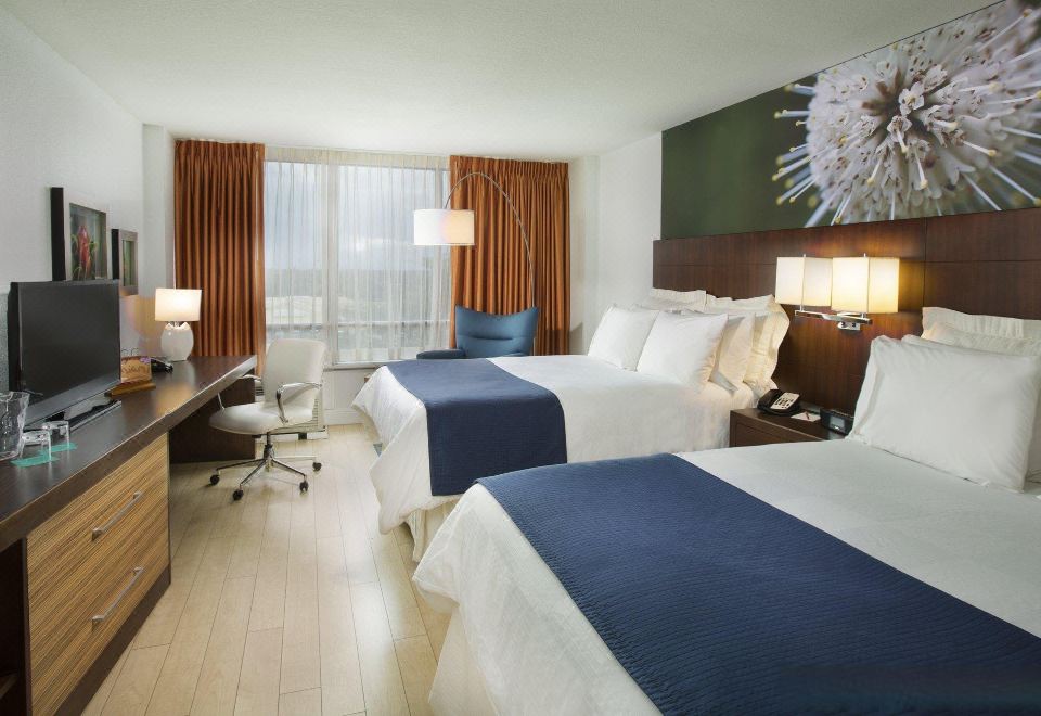 a hotel room with two beds , one on the left and one on the right side of the room at Aloft Miami Dadeland