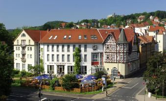 a large white building with a red roof , surrounded by trees and other buildings in the background at Glockenhof