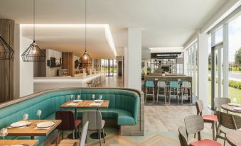 a modern restaurant with a bar and dining area , featuring blue booths and wooden chairs at Hampton by Hilton  Edinburgh Airport