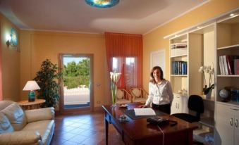 a woman is standing in a well - lit office , working on a laptop while holding a clipboard at Marin Hotel