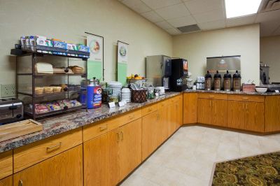 a breakfast buffet with various food items and beverages , including coffee , juice , and pastries , displayed in wooden cabinets at Country Inn & Suites by Radisson, Watertown, SD