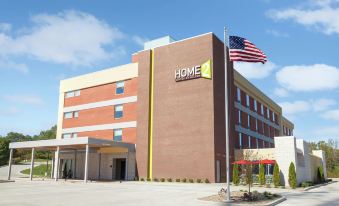 a brick building with an american flag flying in front of it , possibly a hotel at Home2 Suites by Hilton Canton