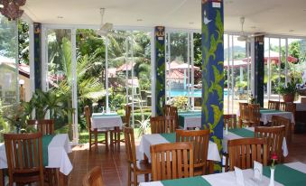 a restaurant with tables and chairs , all set up for dining , and a large window overlooking a pool at Top Resort