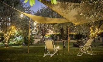 a lawn with a wooden table and chairs under a yellow tarp , surrounded by trees and bushes at Smy Civico Zero