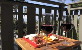 a wooden table with two glasses of red wine and a plate of cheese and crackers at The Olympia Lodge