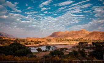 a beautiful landscape with a river flowing through a valley , surrounded by mountains and clouds at River Rock Resort