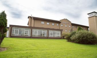 "a large building with a brown roof and the word "" teale "" on it is surrounded by green grass" at Cairn Hotel