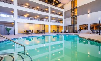 an indoor swimming pool surrounded by a hotel lobby , with several chairs placed around the pool area at Holiday Inn Morgantown - Reading Area