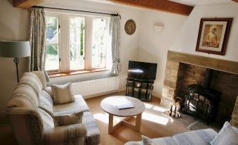 a cozy living room with two couches , a coffee table , and a flat - screen tv mounted on the wall at Ashfield House