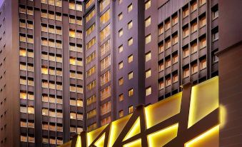 There is a building with two tall structures in the front and one on the side, which is illuminated at Park Hotel Hong Kong