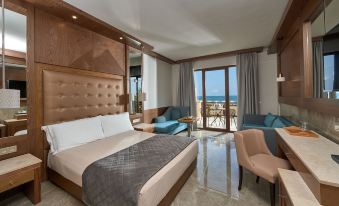 a luxurious hotel room with a large bed , couch , and balcony offering an ocean view at Mediterranean Village Hotel & Spa