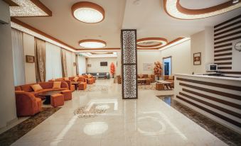 a spacious room with orange couches and chairs , a white tiled floor , and large windows at Continental Hotel