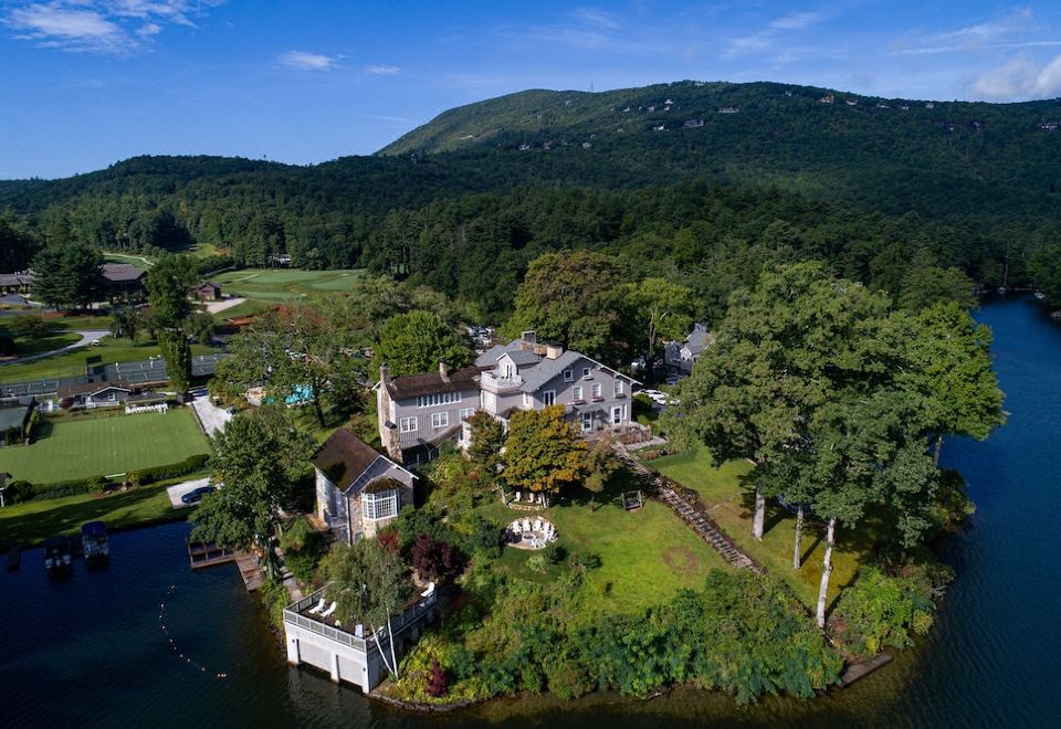 aerial view of a large white house surrounded by trees and grass , situated next to a body of water at The Greystone Inn