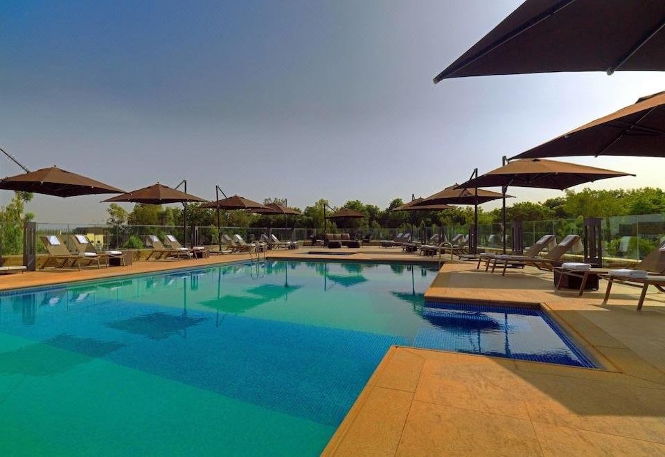 a large swimming pool with lounge chairs and umbrellas is shown in front of trees at Radisson Blu Hotel, Bamako