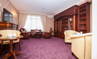 a well - appointed living room with purple carpet , white furniture , and a large window overlooking the city at Savoy Hotel