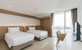 a hotel room with two beds , one on each side of the room , and a chair in the corner at Rattanachol Hotel