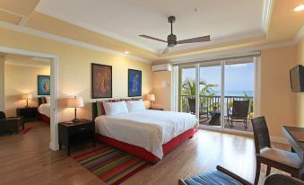 a bedroom with a large bed , a balcony , and a view of the ocean through a sliding glass door at Lime Tree Bay Resort