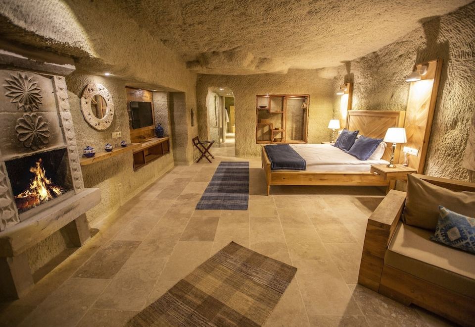 a luxurious bedroom with a king - sized bed , a flat - screen tv mounted on the wall , and a bathroom nearby at Azure Cave Suites - Cappadocia