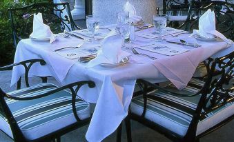 a dining table set for a formal dinner , with multiple plates , forks , knives , and cups placed on the table at White Inn