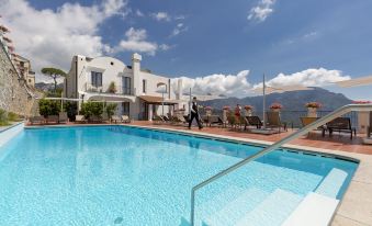 a large swimming pool surrounded by several buildings , with several people enjoying their time in the pool area at Villa Piedimonte