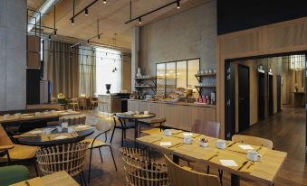 a modern cafe with wooden tables and chairs , a counter filled with various food items , and large windows at Novotel Annemasse Centre - Porte de Genève