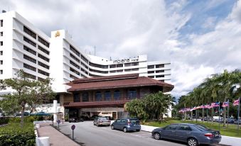 a large hotel building situated on the side of a road , surrounded by trees and parked cars at Impiana Hotel Ipoh