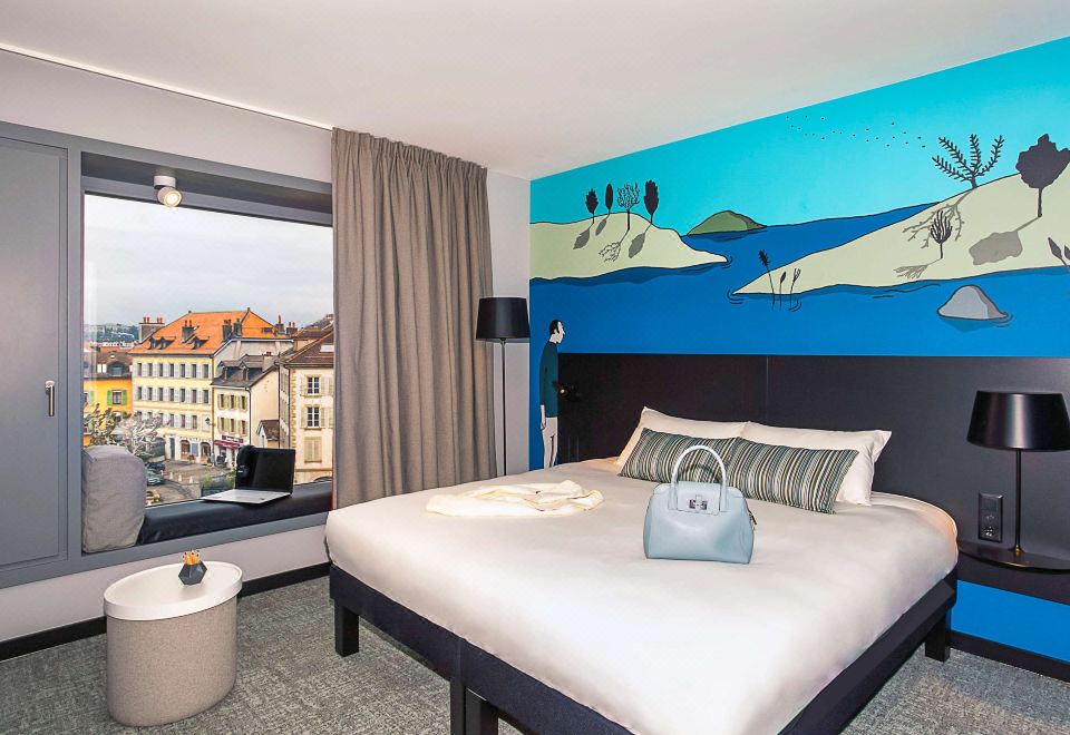 a hotel room with a large bed , a window , and a city view outside the window at Ibis Styles Geneve Carouge