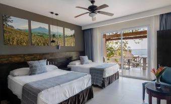 a hotel room with two twin beds , a television , and a balcony overlooking the ocean at Palo Verde Sustainable Hotel