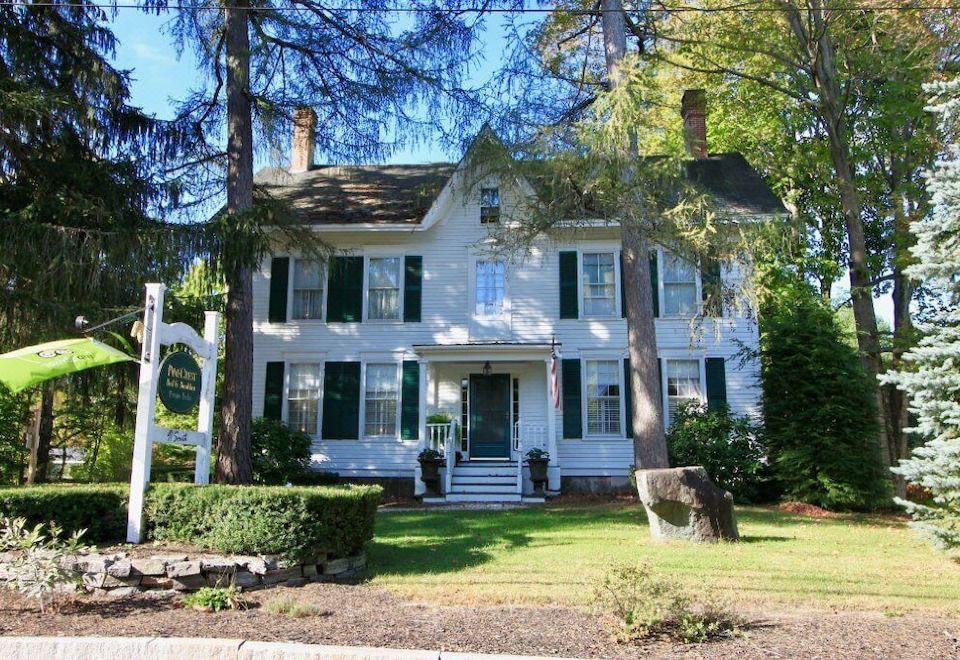 a large white house with green shutters and a stone mailbox on the side of the road at PineCrest Inn