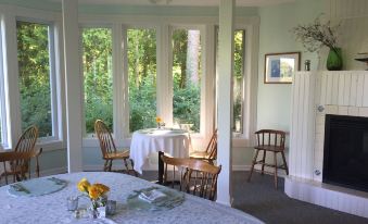 a dining room with a round table surrounded by chairs , and a television mounted on the wall at Victorian by the Sea