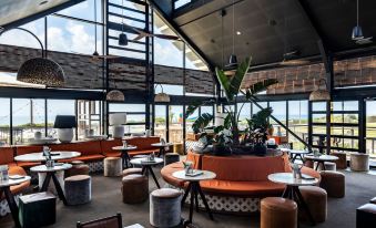 a modern restaurant with an orange and black color scheme , featuring large windows offering views of the city at Caves Coastal Bar & Bungalows