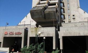 a large concrete building with a metal structure attached to it , situated in a city setting at Zlatibor Hotel
