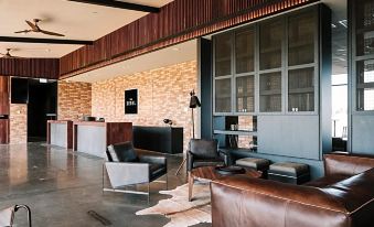 a modern living room with a leather couch , chairs , and a wooden bar in the background at The Sebel Yarrawonga Silverwoods