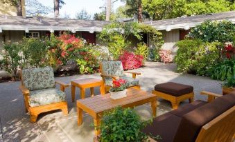 a patio with several chairs and a dining table set up for outdoor dining , surrounded by lush greenery at The Cottages Hotel